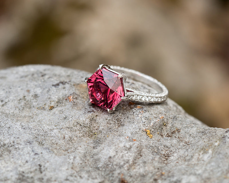 Silver ring with a red gemstone on a rock