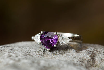 Silver ring with a purple gemstone on a textured surface